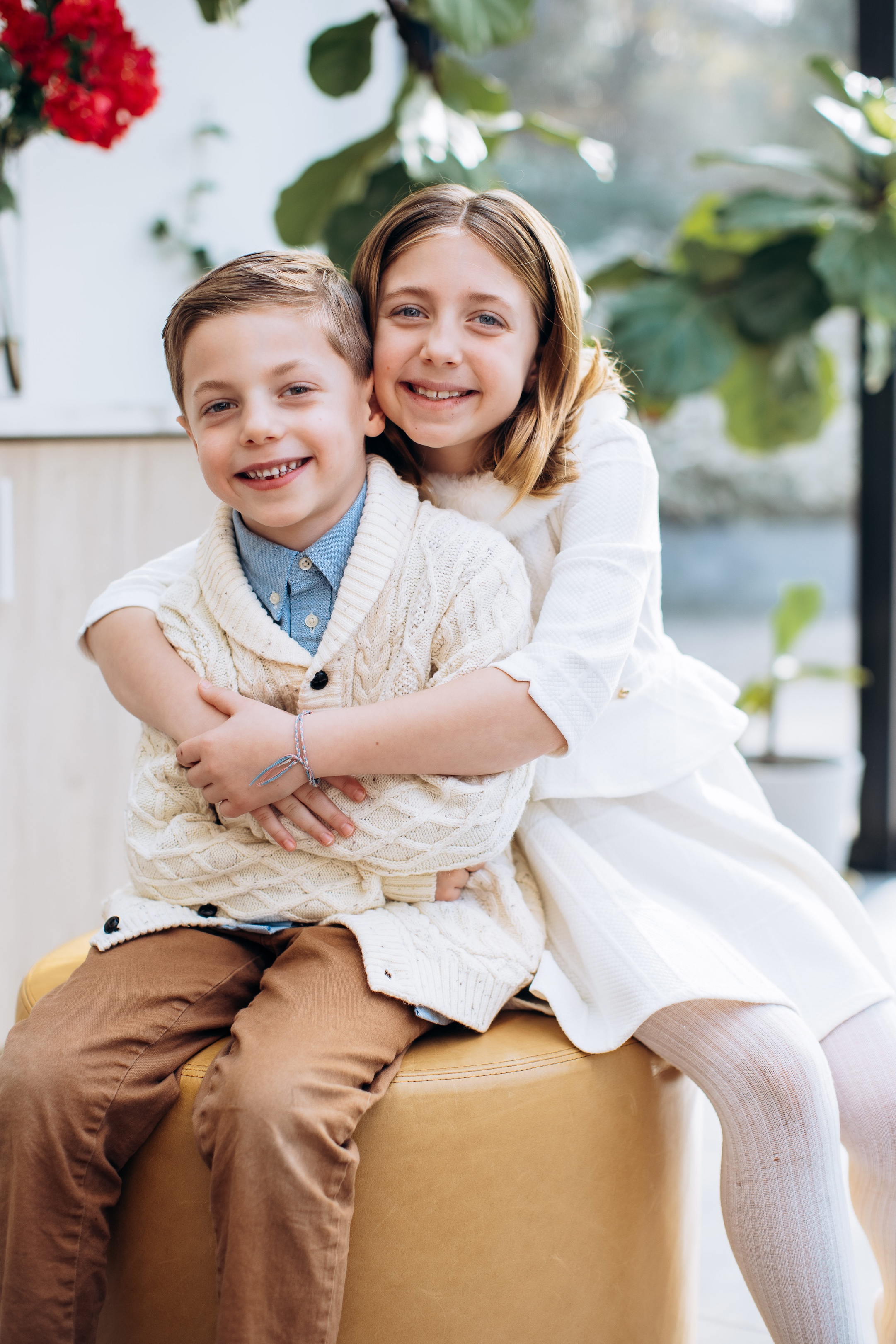 Big sister and her little brother embracing inside their home