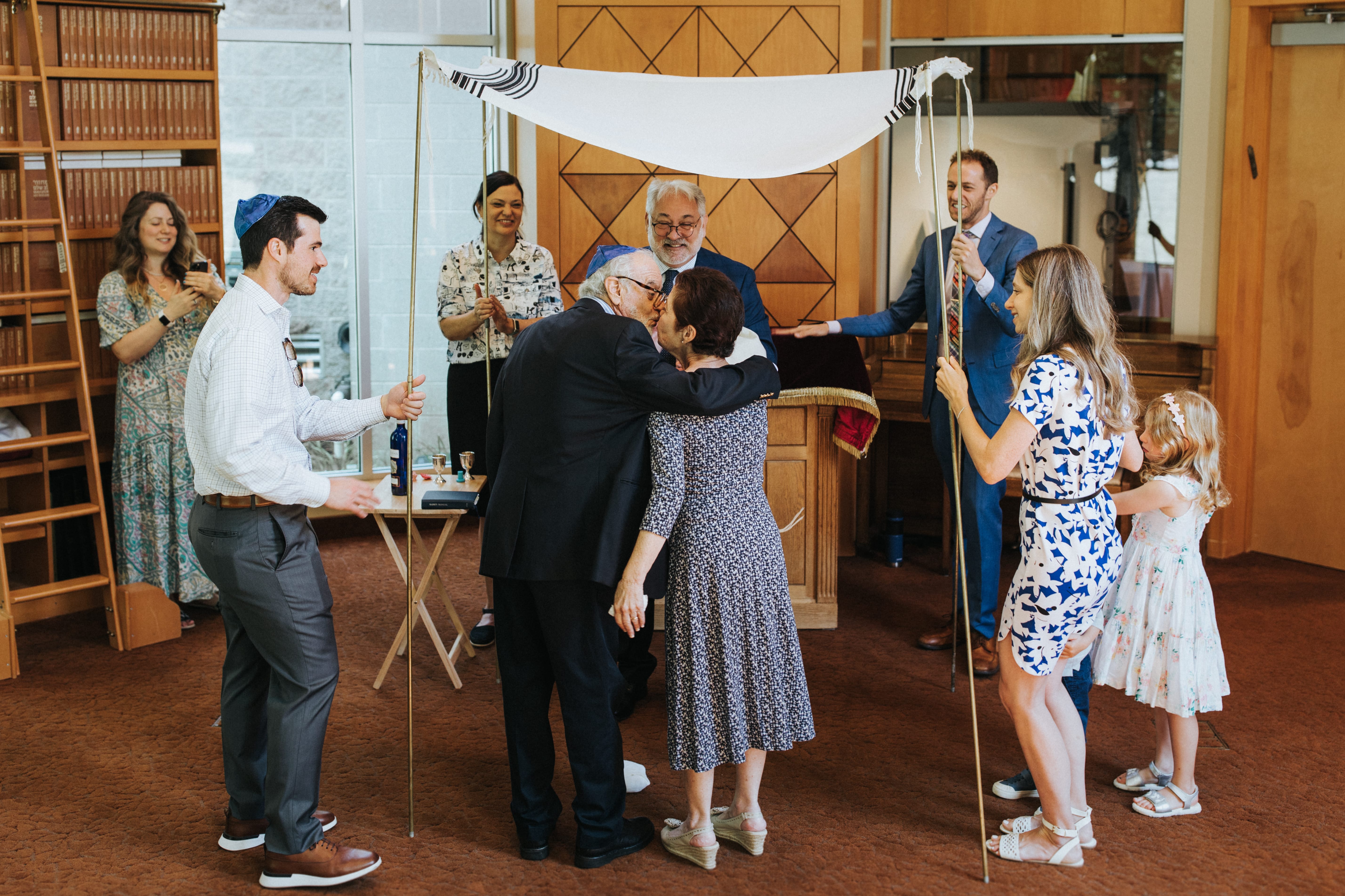 Couple embracing beneath a chuppah during a Jewish wedding ceremony