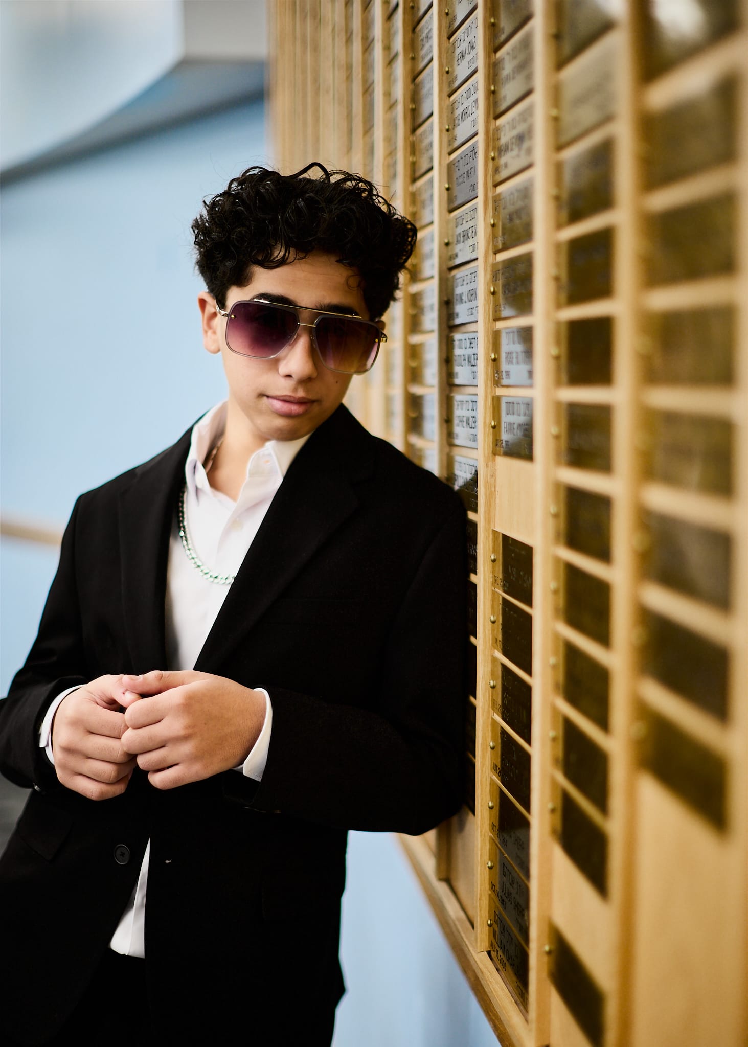 Young man wearing sunglasses and posing in front of books after his Bar Mitzvah ceremony