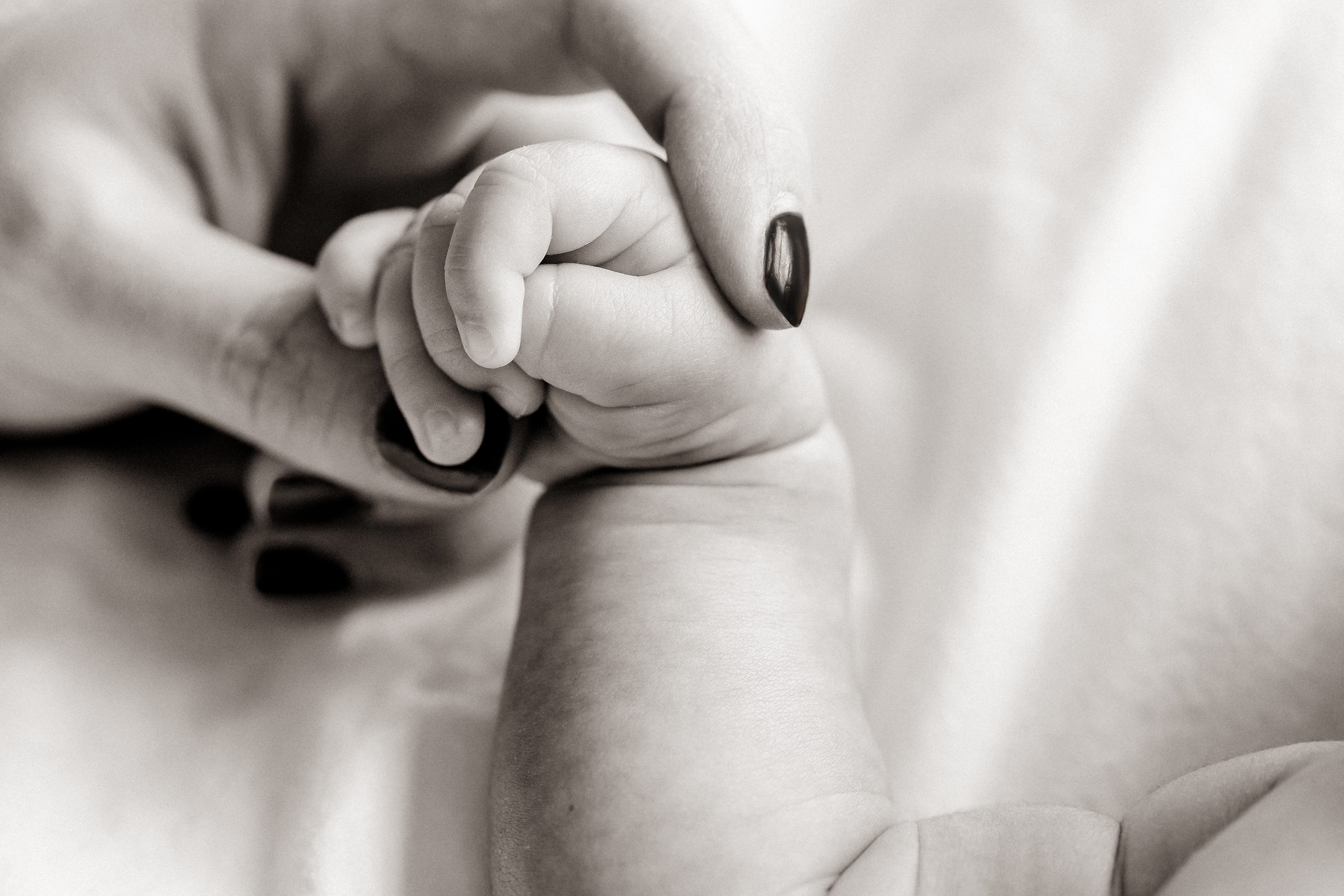 Newborn closeup of mother holding newborn hand